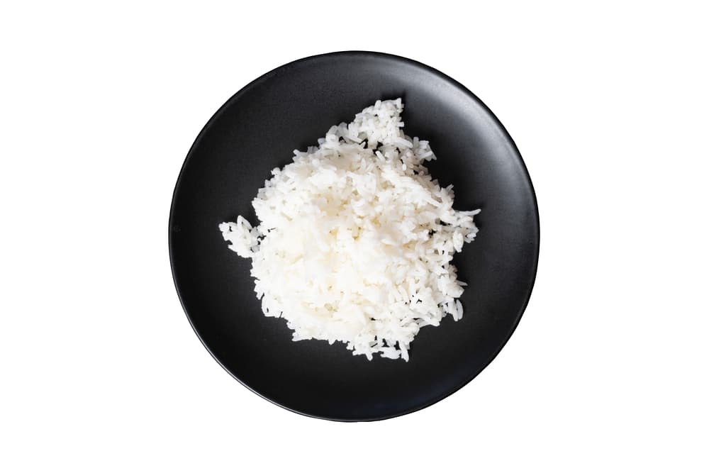黒いお皿に乗ったご飯粒の画像