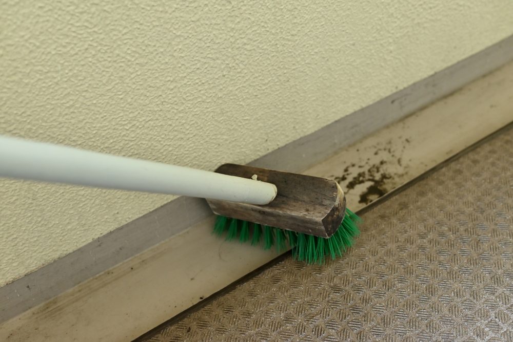 デッキブラシでベランダの溝を掃除する様子