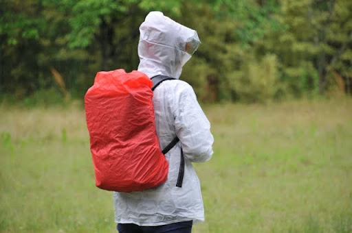 雨の中、透明なレインコートと赤いリュックを背負ってる人