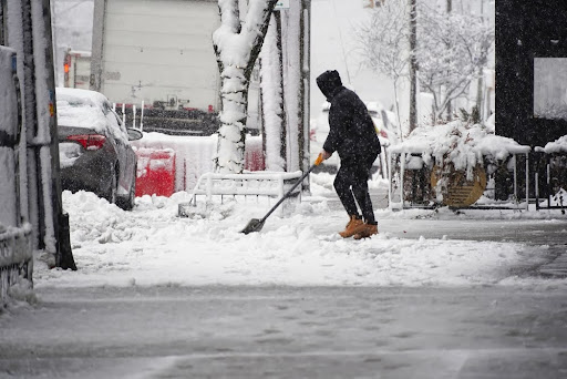 道路に積もった雪をシャベルで取り除く人