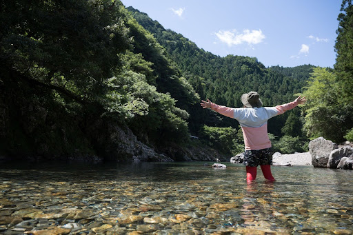 ラッシュガードを着用し、浅瀬の川で遊ぶ人