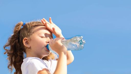 快晴な青空の下で飲み物を飲む小さい子