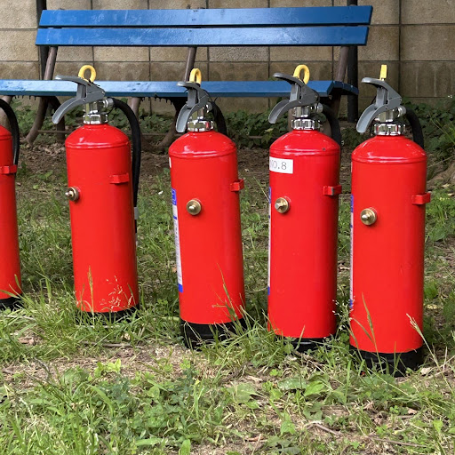 公園のベンチの前に並べてある五つの消火器