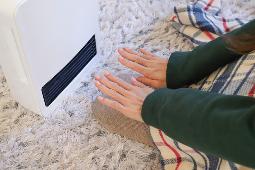 ヒーターで手を温めている