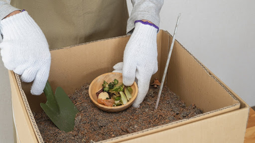 “ダンボールコンポストに生ごみを入れる様子"