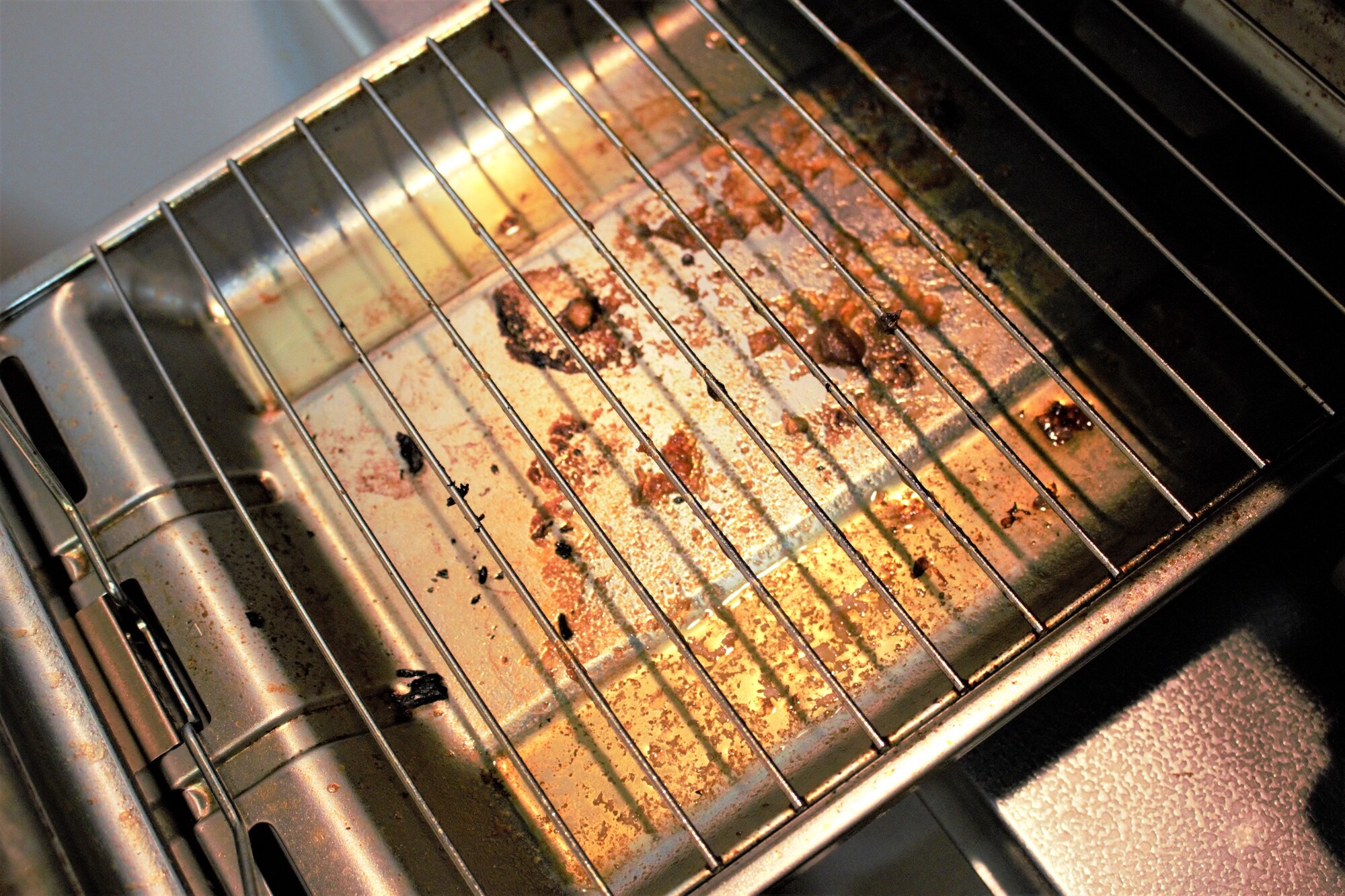 焦げや油汚れが付着した魚焼きグリルの網と受け皿
